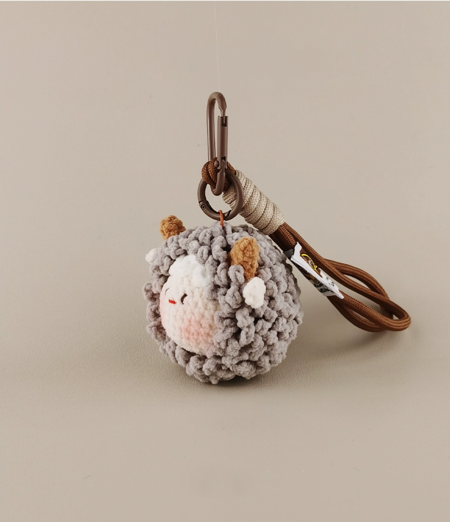Cute little sheep amigurumi keychain, woolen ball with brown leather lanyard and carabiner hook, gray, white, and beige color scheme, simple background, cute style, high-definition photography, cute pet accessories, simple composition, high resolution.