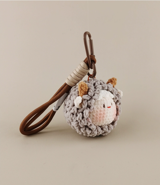 Cute little sheep amigurumi pendant, made of woolen material with a leather lanyard, in a cute and simple style, with a beige-gray color scheme, against a white background, captured in high-definition photography.