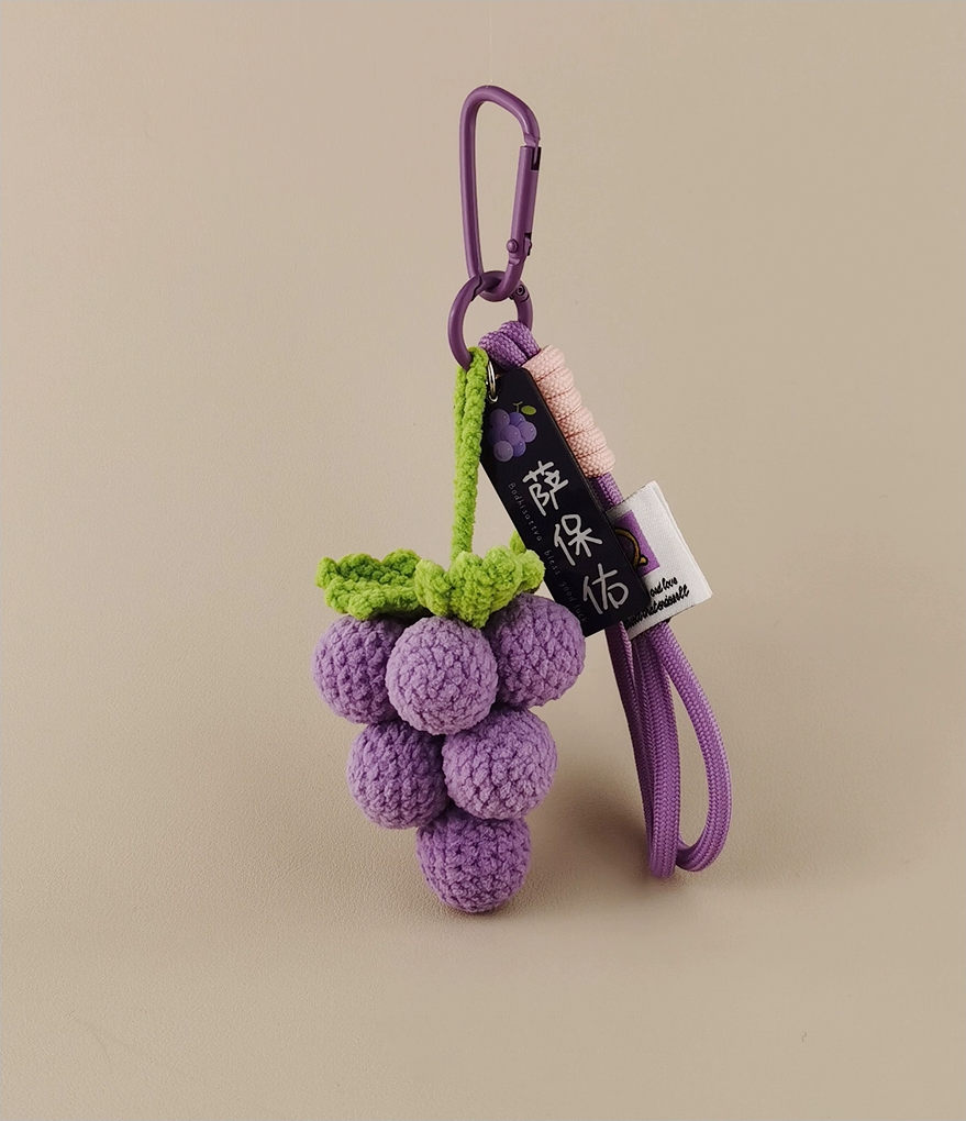 Cute purple grape amigurumi with a tag and lanyard, realistic photograph