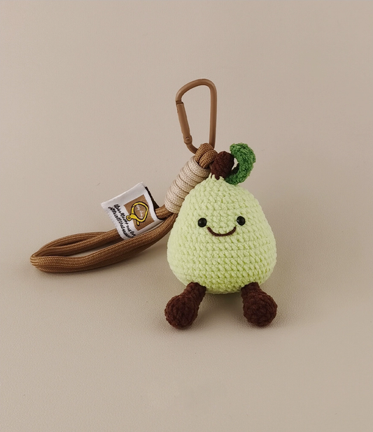 Cute, kawaii-style amigurumi green pear with brown string and tag, on a plain background.