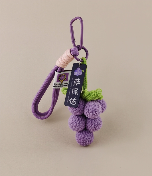 Wine grape keychain, purple with green highlights, crocheted style, tag hanging on the vine with the text "Uva Huilen" (a made-up word), product photography, simple background, high resolution, highly detailed.